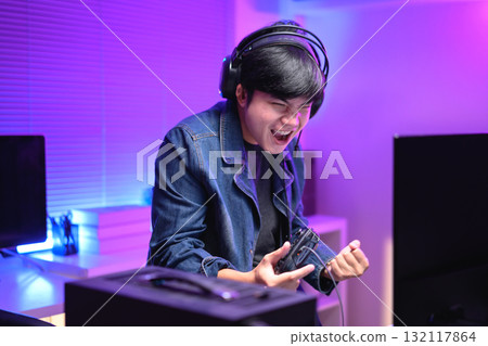 Excited gamer celebrating victory after winning video game at night, 132117864