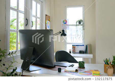 Top view of creative workspace with color palette, digital tablet, and notebook sketching logo design on clean white desk 132117875