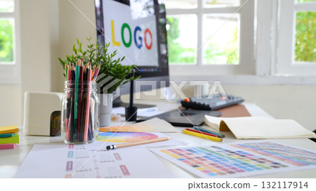 Creative woman designing logo sketches on notebook with color samples and tools in bright modern workspace Creative woman designing logo sketches on notebook with color samples and tools in bright modern workspace 132117914