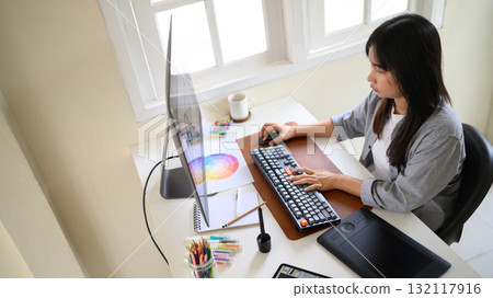 Female graphic designer working on computer with color palette and tablet 132117916