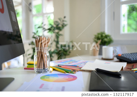 Creative woman designing logo sketches on notebook with color samples and tools in bright modern workspace 132117917