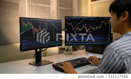 Cropped shot young man trader analyzing financial charts on computer at night, focused on investment strategy 132117936