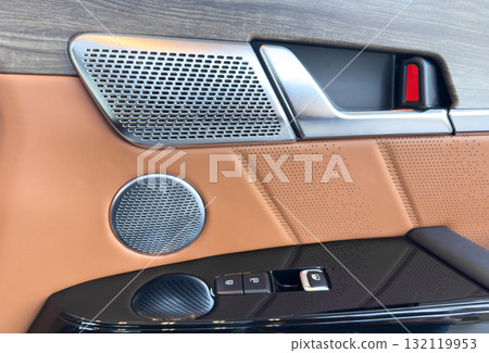 Car door handle inside the luxury modern car with brown leather. Switch button control. Modern car interior details. Brown perforated leather Car door handle inside the luxury modern car with brown leather. Switch button control. Modern car interior details. Brown perforated leather 132119953