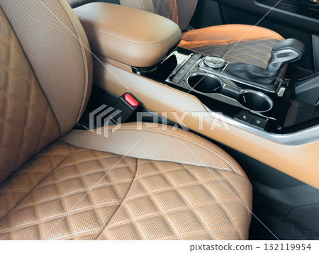 Luxury car  brown leather interior. Part of brown leather car seat details with stitching isolated on black. Interior of prestige car. Comfortable perforated leather seats. Perforated leather. 132119954