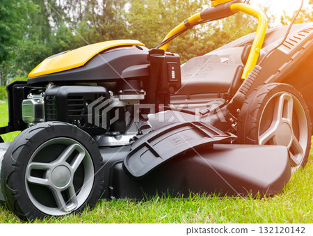 Mowing lawns. Lawn mower on green grass. Mower grass equipment. Mowing gardener care work tool close up view. Soft lighting Mowing lawns. Lawn mower on green grass. Mower grass equipment. Mowing gardener care work tool close up view. Soft lighting 132120142