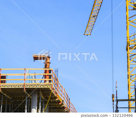 Construction crane tower on blue sky background. Crane and building working progress. Worker. Construction concept. New buildings with a crane. Tower crane 132120466