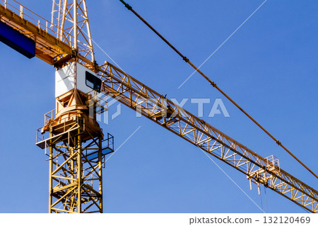 Construction crane tower on blue sky background. Crane and building working progress. Worker. Construction concept. New buildings with a crane. Tower crane 132120469