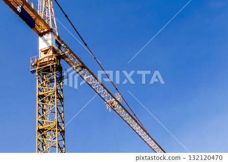 Construction crane tower on blue sky background. Crane and building working progress. Worker. Construction concept. New buildings with a crane. Tower crane 132120470