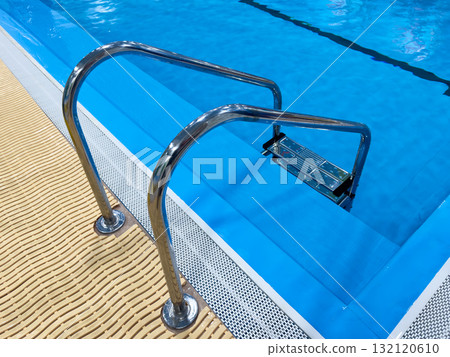 Swimming pool with stair and water. Swimming pool with handrail. Stainless steel ladder in pool. Grab bars ladder in the blue swimming pool 132120610