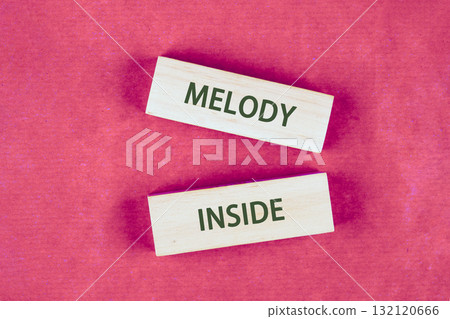 Two wooden blocks are positioned on a bright pink surface, featuring the words Melody and Inside in bold letters, inviting reflection on creativity and personal inspiration 132120666