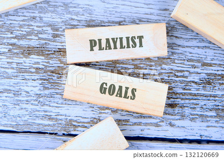 Wooden blocks positioned on a weathered surface display the words playlist goals, suggesting a fun, artistic activity. This scene invites creativity and musical inspiration Wooden blocks positioned on a weathered surface display the words playlist goals, suggesting a fun, artistic activity. This scene invites creativity and musical inspiration 132120669