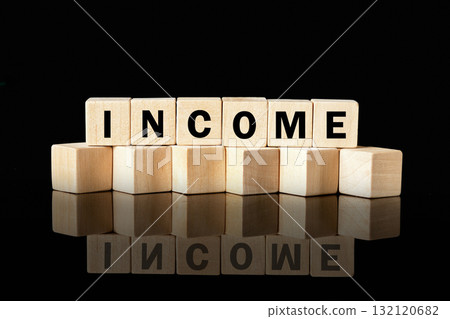 Wooden blocks arranged to spell out the word income create a striking visual against a glossy black background, emphasizing financial themes and concepts of wealth 132120682