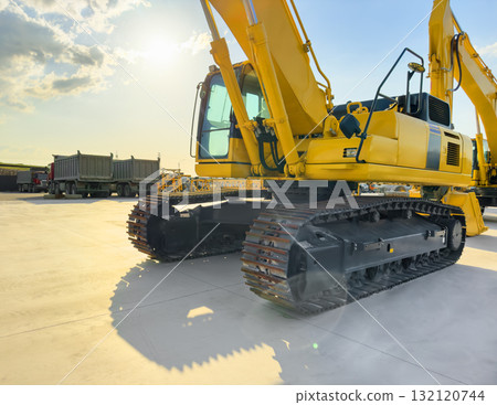 Crawler excavator with lift up bucket at construction site. Powerful excavator with an extended bucket close-up at the sunset. Construction equipment for earthworks 132120744