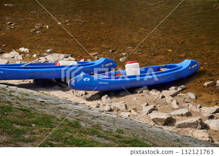 Two blue kayaks resting on a rocky riverbank of Vltava river in Cesky Krumlov in South Bohemia in Czech Republic 132121763