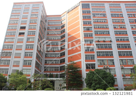 A tall, modern apartment building with many windows and balconies, featuring a striking orange and grey facade A tall, modern apartment building with many windows and balconies, featuring a striking orange and grey facade 132121981