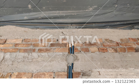 Exposed brick wall with cement repairs and a blue pipe running vertically through the center area Exposed brick wall with cement repairs and a blue pipe running vertically through the center area 132122365
