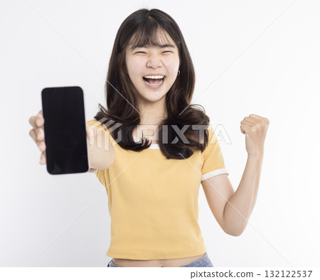 Asian girl showing or presenting mobile phone application and success gesture isolated over white background Asian girl showing or presenting mobile phone application and success gesture isolated over white background 132122537