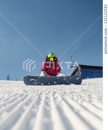 Snowboarder preparing for an exciting descent on a pristine snow-covered slope under clear blue skies 132122582