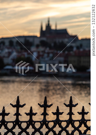 Silhouette of a fence with blurred Vltava river and Prague castle at sunset in Prague, Czech Republic Silhouette of a fence with blurred Vltava river and Prague castle at sunset in Prague, Czech Republic 132122632