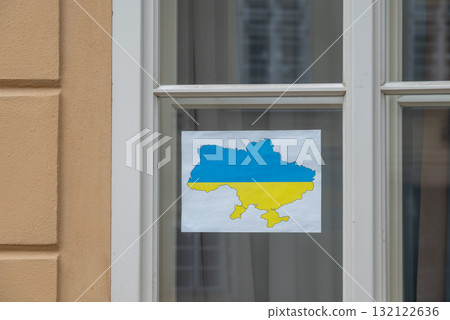 Paper with the map of Ukraine in blue and yellow colors of Ukrainian flag taped to a window as symbol of support of Ukraine 132122636