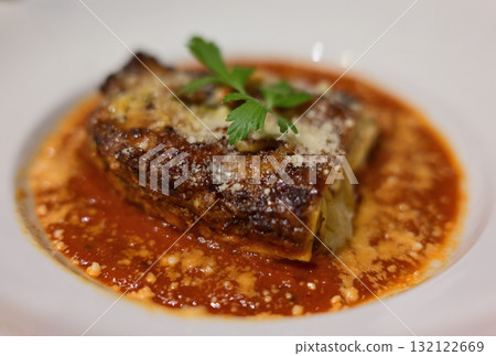 Slice of lasagna with tomato sauce and parsley garnish Slice of lasagna with tomato sauce and parsley garnish 132122669