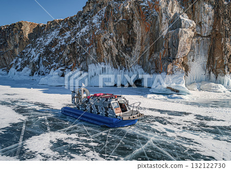 Hovercraft parked on a blue cracked ice of the lake Baikal. Tourists transportation and entertainment on winter Baikal. Hovercraft parked on a blue cracked ice of the lake Baikal. Tourists transportation and entertainment on winter Baikal. 132122730