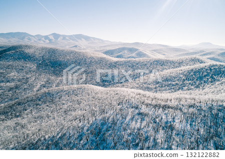 Aerial view of a snow-covered mountain landscape under clear blue sky in winter season 132122882