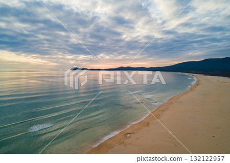Beautiful coastal sunset with soft waves and serene landscape captured in the evening sky Beautiful coastal sunset with soft waves and serene landscape captured in the evening sky 132122957