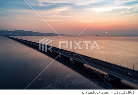 Aerial drone view of low-water bridge across the bay with moving car during the sunset. Active movement of transport cars vehicles in different directions. 132122961