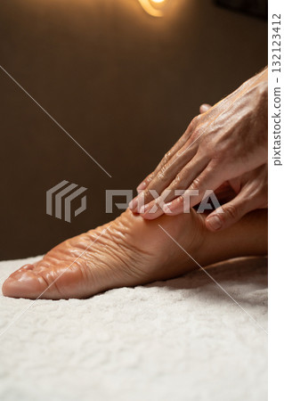 Close-up of a foot massage in a spa, therapist gently massaging the heel with oil, relaxation and wellness concept, warm light atmosphere, skin care and body therapy. Close-up of a foot massage in a spa, therapist gently massaging the heel with oil, relaxation and wellness concept, warm light atmosphere, skin care and body therapy. 132123412