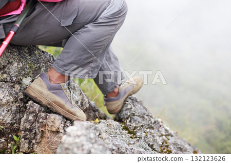 Close up of hiker resting on rocky cliff in hiking shoes, symbol of adventure, outdoor lifestyle, challenge, exploration, determination, nature journey and freedom in mountain travel. 132123626