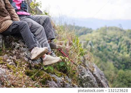 Close up of hiker resting on rocky cliff in hiking shoes, symbol of adventure, outdoor lifestyle, challenge, exploration, determination, nature journey and freedom in mountain travel. Close up of hiker resting on rocky cliff in hiking shoes, symbol of adventure, outdoor lifestyle, challenge, exploration, determination, nature journey and freedom in mountain travel. 132123628