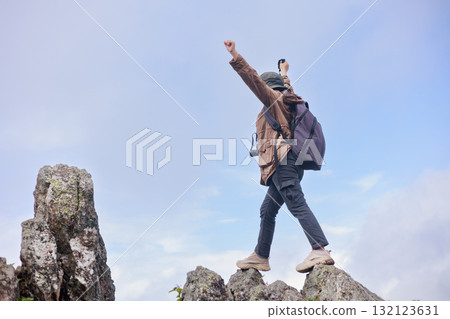 Hiker standing on rocky cliff with trekking pole, symbol of adventure, confidence, challenge, exploration, outdoor lifestyle, success and travel inspiration in mountain nature. 132123631