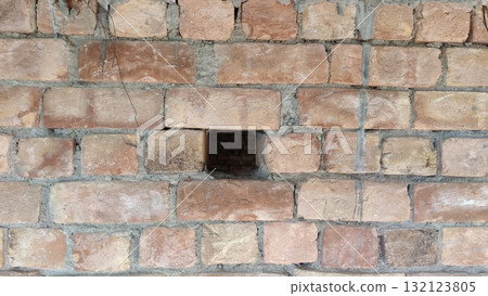 Close up view of a brick wall with a dark rectangular hole in the middle of the structure design Close up view of a brick wall with a dark rectangular hole in the middle of the structure design 132123805