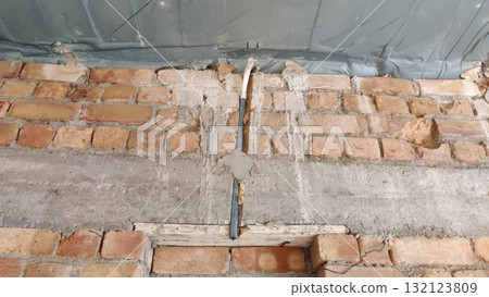 Exposed brick wall with cement repairs and a blue pipe running vertically through the center area Exposed brick wall with cement repairs and a blue pipe running vertically through the center area 132123809