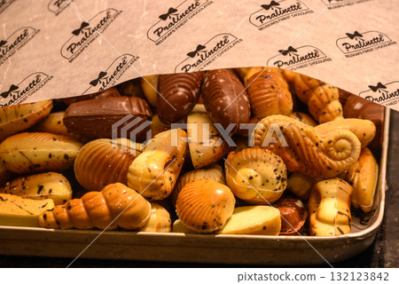 Assorted Belgian chocolate pralines in various shapes under branded paper in Bruges, Belgium 132123842