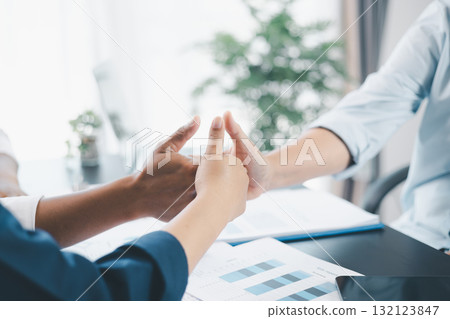 Business teamwork concept with three colleagues doing thumbs up together in office, symbol of partnership, trust, support and successful collaboration with financial reports on desk. 132123847