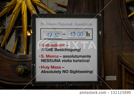 Sign at St. Johann Nepomuk Asamkirche catholic church, with service times and no sightseeing notice in Munich, Germany 132123890