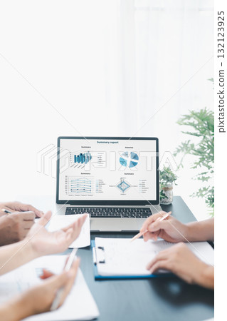 Business data analysis concept with colleagues reviewing financial report on laptop, pointing at chart with growth graph, teamwork discussing statistics, planning strategy and corporate success. 132123925