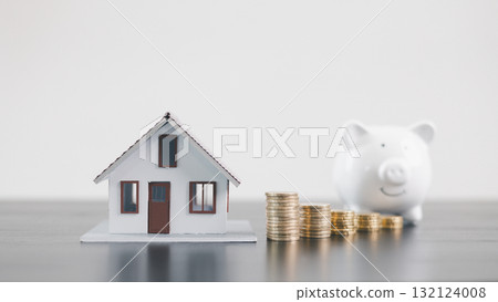 Mini house model with coins and white piggy bank, representing mortgage loan, real estate investment, property finance, savings, insurance, wealth management and housing economy concept. Mini house model with coins and white piggy bank, representing mortgage loan, real estate investment, property finance, savings, insurance, wealth management and housing economy concept. 132124008