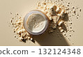 Scattered beige powder and clear jar on pastel background in natural light, symbolizing beauty or supplement concept 132124348