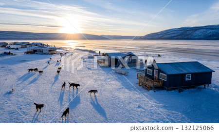 Traditional indigenous settlement in permafrost with wooden cabins, huskies, and icy terrain under a pale winter sun. Life in permafrost conditions, climate change problems on the planet. Global 132125066