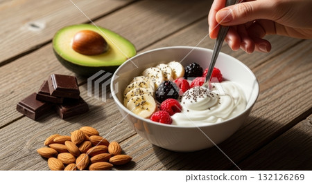 Nutritious breakfast bowl with yogurt, fresh berries, banana, chia seeds, avocado, and almonds. 132126269