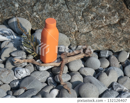 Plastic orange beauty bottle against backdrop of natural elements. Cosmetics and facial and hair care. Mock-up template for design. Eco-friendly products. Background, design composition. 132126407