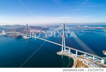 Stunning view of the Russky Bridge in Vladivostok with clear blue skies and tranquil waters. Stunning view of the Russky Bridge in Vladivostok with clear blue skies and tranquil waters. 132126719
