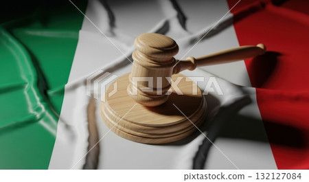 Wooden gavel and sounding block resting on a draped italian flag, symbolizing justice and law. 132127084