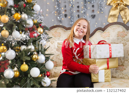 Little girl holding gift boxes near Christmas tree Little girl holding gift boxes near Christmas tree 132127402