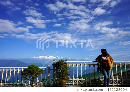 Woman Standing on Terrace Looking at Majestic Snow Capped Kanchenjunga Mountain Peaks from Darjeeling 132128604