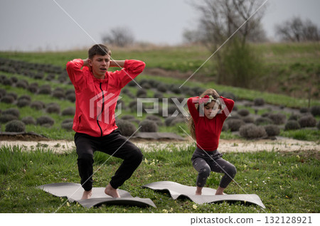 Two individuals practicing exercises outdoors in a calming lavender field during springtime, showcasing teamwork and healthy living amidst nature's beauty Two individuals practicing exercises outdoors in a calming lavender field during springtime, showcasing teamwork and healthy living amidst nature's beauty 132128921