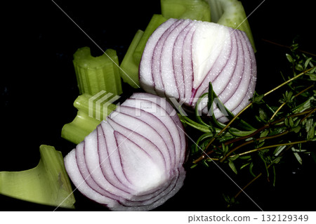 Close up of chopped celery onion and rosemary waiting to be used to cook dinner on a black background Close up of chopped celery onion and rosemary waiting to be used to cook dinner on a black background 132129349